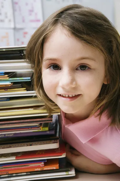 Kleines Mädchen mit einem Stapel Bücher — Stockfoto