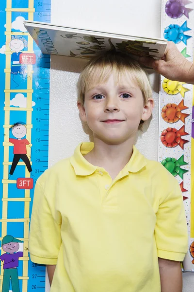 Мальчик получает высоту измеряется учителем — стоковое фото