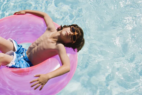 Мальчик на плавучем метро в бассейне — стоковое фото