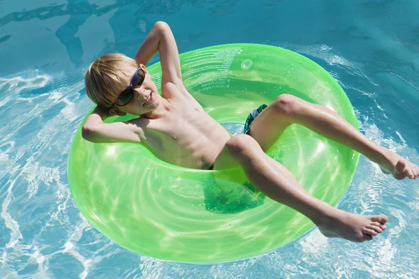 Junge auf Schwimmerrohr im Schwimmbad — Stockfoto