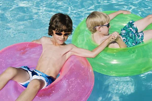 Garçons sur des tubes flottants dans la piscine — Photo