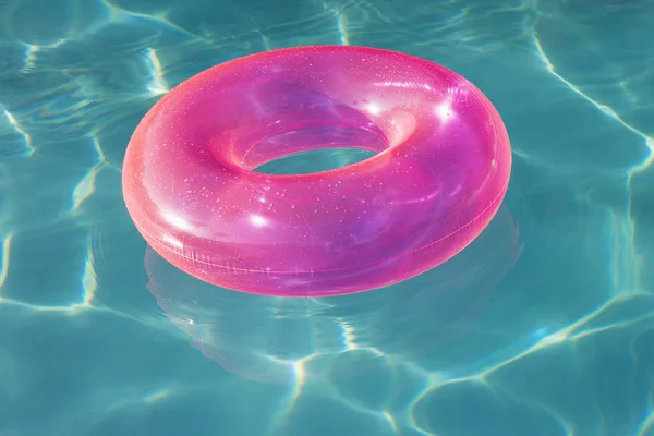 Tubo flutuante rosa flutuando na piscina — Fotografia de Stock
