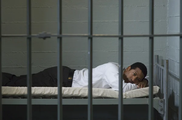 Businessman Lying On Bed In Prison Cell — Stock Photo, Image