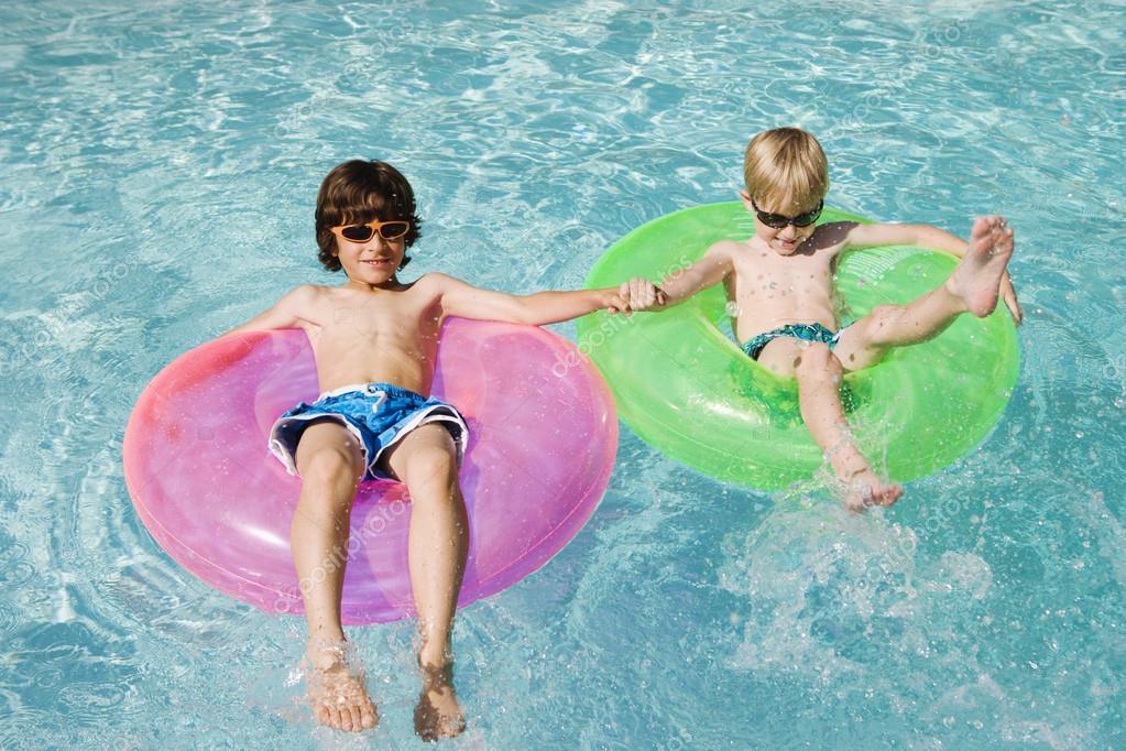 Boys On Float Tubes In Swimming Pool — Stock Photo © londondeposit