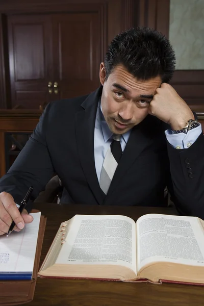 Напряженный адвокат сидит с книгой и записками — стоковое фото