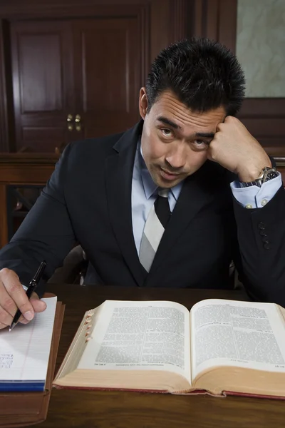 Abogado ensanchado sentado con libro y notas — Foto de Stock