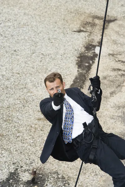 Männlicher Spion zielt beim Abseilen auf Handfeuerwaffe — Stockfoto