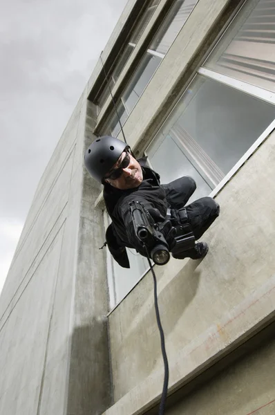 SWAT Oficial de equipo apuntando arma mientras rappel — Foto de Stock