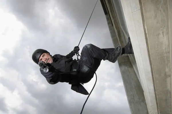 SWAT Oficial de equipo apuntando arma mientras rappel — Foto de Stock