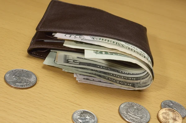 Peněženka plná peněz a mincí na stůl — Stock fotografie