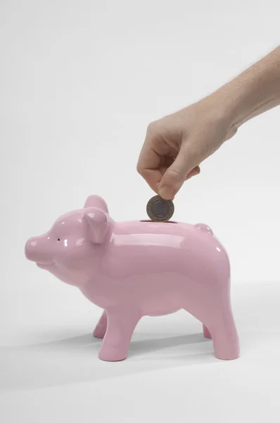 La mano de la mujer insertando moneda en Piggybank — Foto de Stock