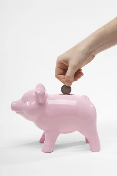 Piggybank でコインを挿入する女性の手のクローズ アップ — ストック写真