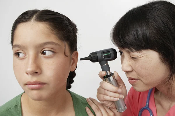 Doutor examinando orelha da menina com otoscópio — Fotografia de Stock