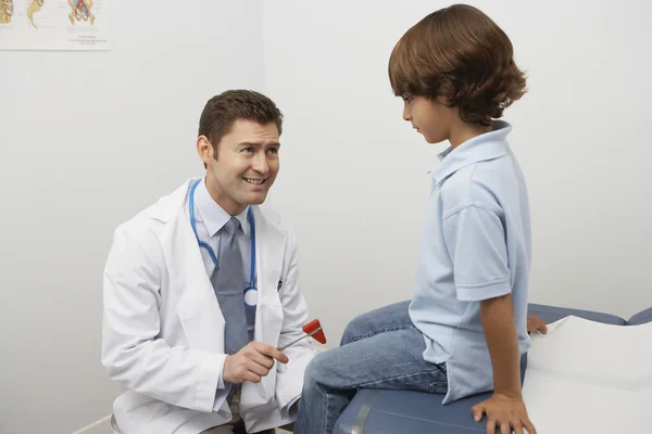 Vyšetřující lékař chlapce s reflexní kladivo — Stock fotografie