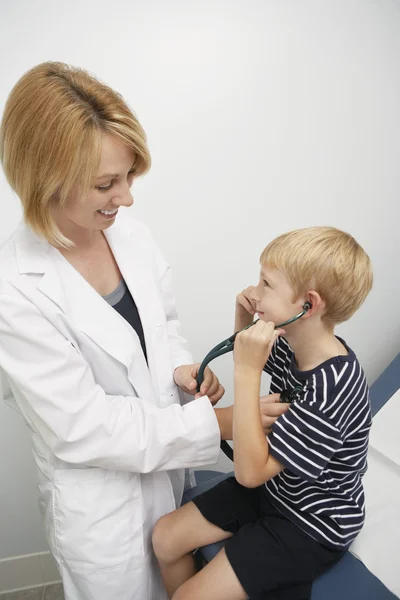 Chico escuchando sus propios latidos del corazón con la ayuda de médico femenino — Foto de Stock