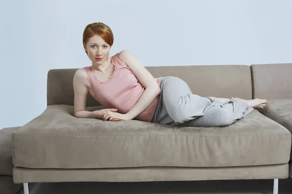 Mladá žena ležící doma na pohovce — Stock fotografie