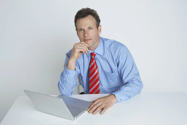 Säker affärsman sitter med laptop på skrivbordet — Stockfoto