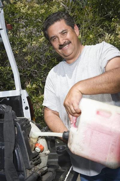 Человек заправляет газонокосилку — стоковое фото