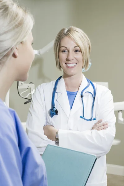 Dentista con le braccia incrociate guardando infermiera — Foto Stock