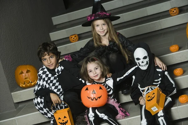 Niños con disfraces de Halloween sentados en las escaleras — Foto de Stock