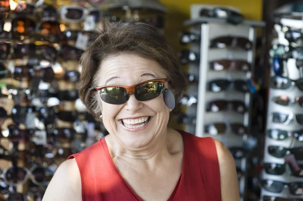 Seniorin probiert Sonnenbrille im Geschäft aus — Stockfoto