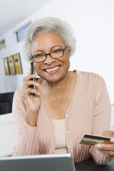 Äldre kvinna shopping online med hjälp av cell telefonerna och kreditkort — Stockfoto