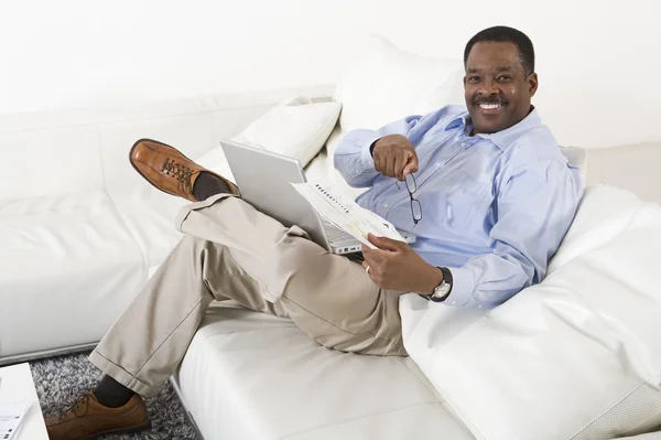 Relaxado homem com laptop sentado no sofá — Fotografia de Stock