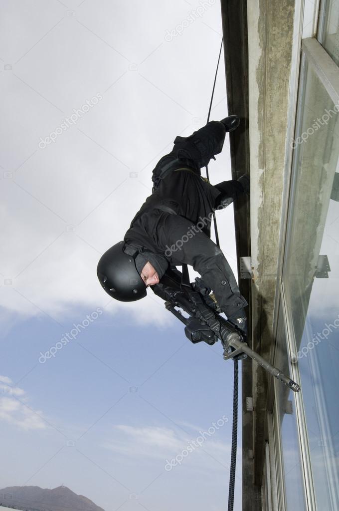 SWAT Team Officer Aiming Assault rifle While Rappelling