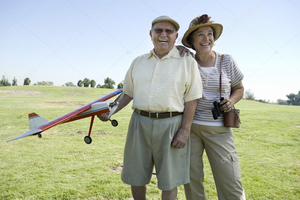 Senior Man Holding Model Plane By Woman On Field