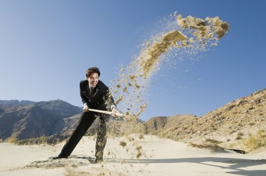 Businessman Using A Shovel In Desert clipart