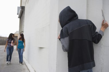 soyguncu köşesinde arkasında saklanıyor ve iki kız için bekleyen bıçak ile