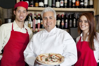 mutlu bir şef pizza ile tutarak portresi beklemek personel