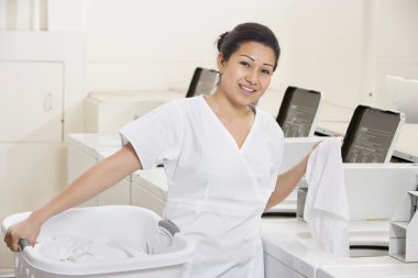Çamaşırhanede çamaşır makineleri tarafından ayakta mutlu bir genç yaş portresi