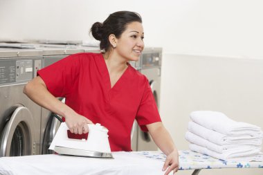 mutlu genç kadın işçiye laundromat uzağa bakarken Ütü