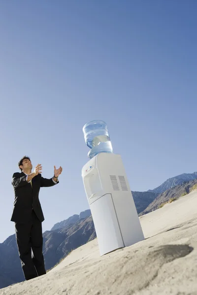 Homme d'affaires debout près du refroidisseur d'eau dans le désert — Photo