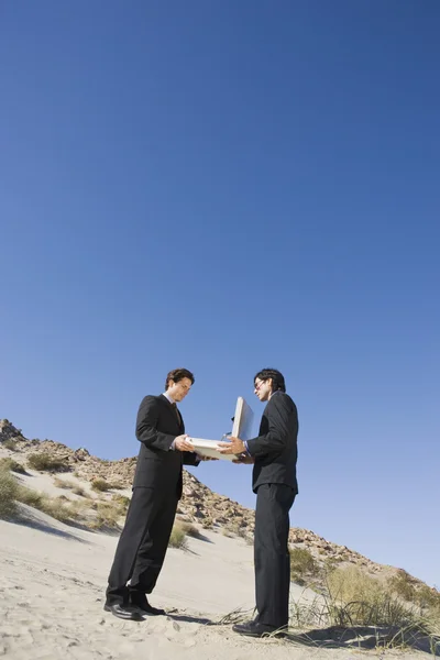 Dos hombres de negocios llevando a cabo maletín abierto en el desierto — Foto de Stock