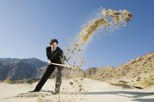 Uomo d'affari che utilizza una pala nel deserto — Foto Stock
