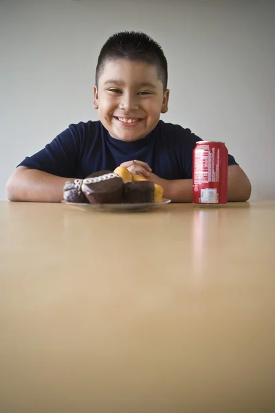 Мальчик с десертом и выпивкой сидит за столом — стоковое фото