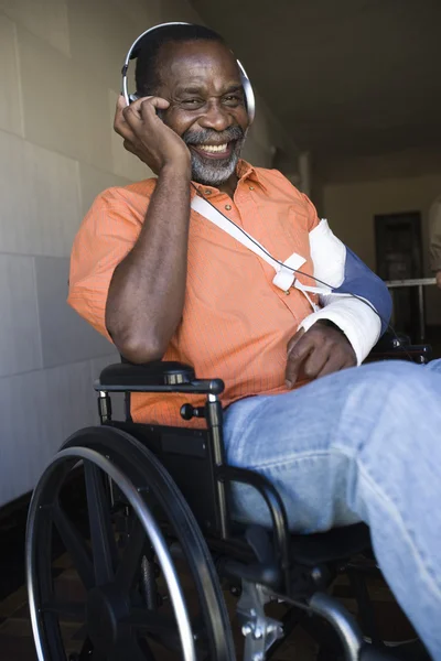 Hombre lesionado escuchando música mientras está sentado en silla de ruedas — Foto de Stock
