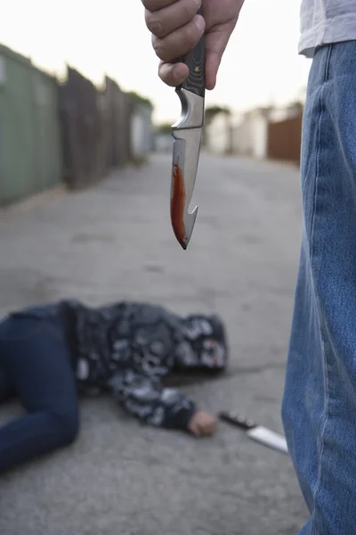Aggressiva kriminella stående bredvid knivhuggen man liggande på marken — Stockfoto