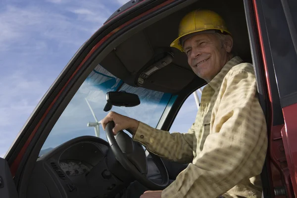 Senior man in vrachtwagen bij windpark — Stockfoto