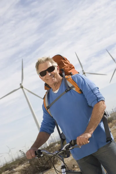 Starszy człowiek z rowerem w farm wiatrowych — Zdjęcie stockowe