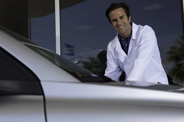 Cheerful car dealer standing besides car — Stock Photo, Image