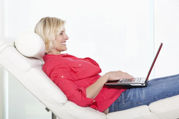 Senior woman lying on chair with laptop — Stock Photo, Image