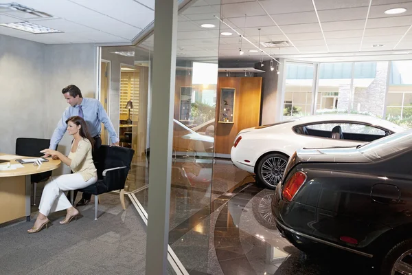 Mulher e vendedor sentado no escritório do showroom do carro — Fotografia de Stock