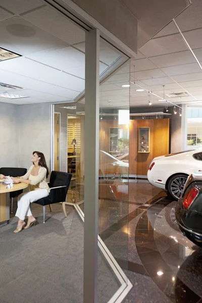 Woman sitting in car showroom office — Stock Photo, Image