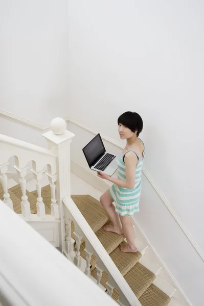 Comprimento total da jovem mulher com laptop subindo escadas — Fotografia de Stock