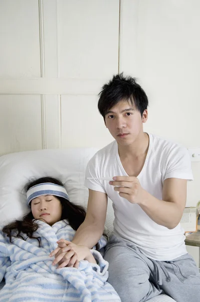 Portrait of young man while woman lying in bed — Stock Photo, Image