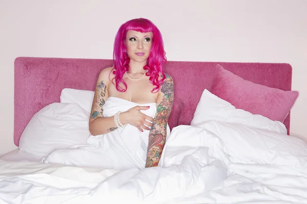 Woman in pink wig sitting in bed — Stock Photo, Image