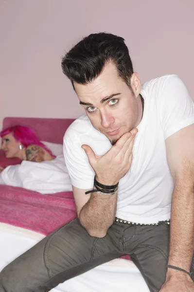 Portrait of man posing while woman lying on bed in the background — Stock Photo, Image